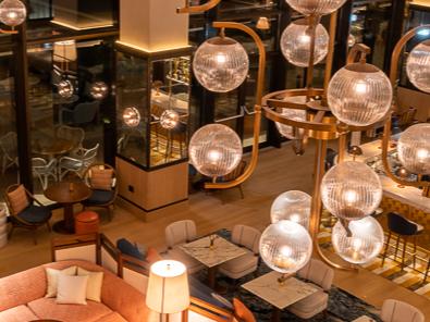 large globe shaped chandelier lights lighting up the cosy relaxing hotel lobby area with sofas and coffee tables